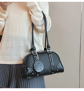 Close-up of black pebble leather texture and silver chain weaving on shoulder bag