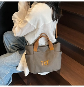 Détail du sac cabas en toile avec broderie TCT orange et bandoulière marron amovible