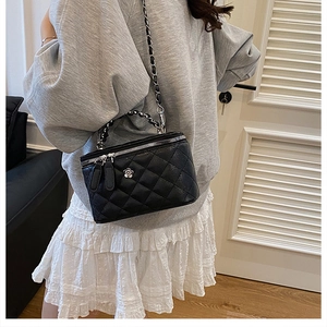Détail du sac seau noir matelassé avec bandoulière chaîne porté par un mannequin
