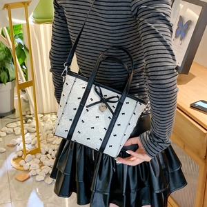 Détail du sac seau en nylon blanc avec nœud noir et pendentif en métal en forme de cœur