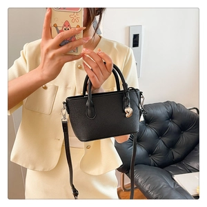Détail du sac seau noir en cuir grainé avec breloque cœur doré et bandoulière