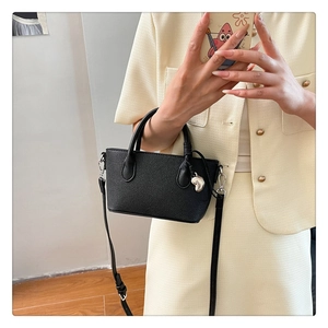 Détail du sac seau noir en cuir avec breloque cœur argentée et bandoulière réglable