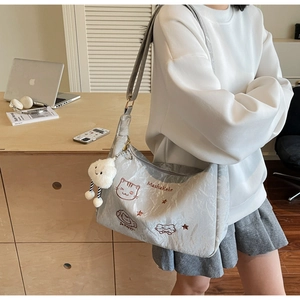Close-up of light gray tote bag featuring cat embroidery and cloud plush charm detail
