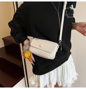 Close-up of off-white lychee leather crossbody bag featuring a cute elephant charm