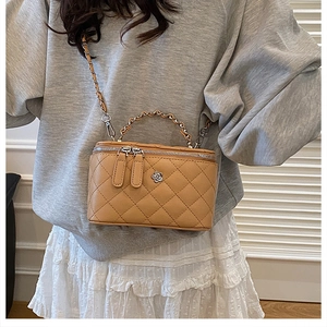 Détail du sac seau en cuir matelassé marron clair avec logo fleur argenté et bandoulière