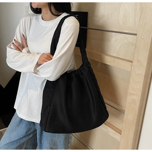 Detailed close-up of a large black hollow nylon mesh tote bag worn by a model
