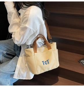 Détail du sac fourre-tout en toile beige avec broderie TCT bleue et poche latérale brune