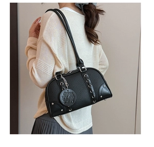 Detail view of black lychee grain leather shoulder bag with metallic eyelet decorations