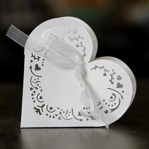 Close-up of white heart-shaped hollow gift box with glitter finish and ribbon
