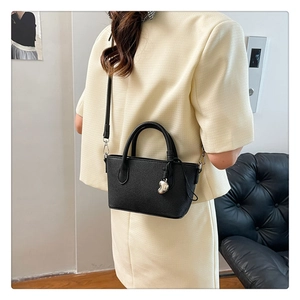 Détail du sac seau noir en cuir grainé avec breloque cœur argentée et bandoulière réglable