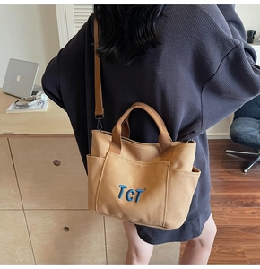 Détail du sac fourre-tout en toile kaki avec broderie TCT et bandoulière amovible