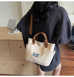 Détail du sac bandoulière en toile crème avec broderie TCT et bandoulière tissée marron
