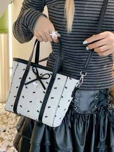 Sac fourre-tout blanc en nylon avec motifs nœuds noirs et pendentif cœur porté en bandoulière