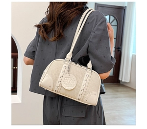 Close-up of a cream white pebble leather shoulder bag styled on a model in a modern room