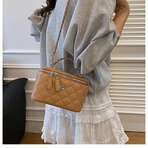 Détail du sac seau matelassé caramel avec bandoulière chaîne et pendentif fleur