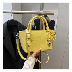 Détail du sac à main en cuir grainé jaune vif avec breloque cœur et bandoulière