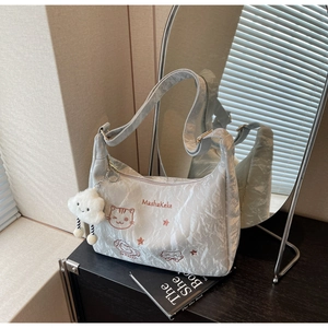 Detail of silver tote bag with cat embroidery, cloud charm, and pleated fabric texture