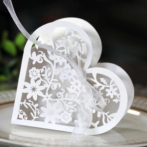 Detail of white laser-cut hollow heart gift box with elegant organza ribbon and glitter finish