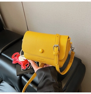 Detail of yellow lychee texture leather crossbody bag with cute red elephant charm