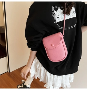 Sac à bandoulière rose texture litchi porté par un mannequin pour un look décontracté