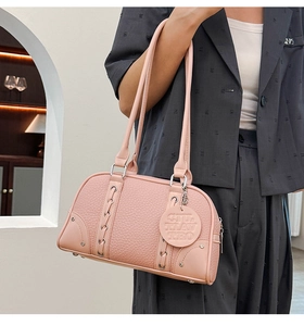 Detail of pink pebbled leather Boston bag featuring cross lace-up design and silver rings