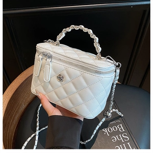 Détail du sac seau blanc en cuir matelassé avec logo fleur en métal et bandoulière