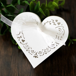 Detail view of pink heart-shaped laser-cut favor box with white organza ribbon bow