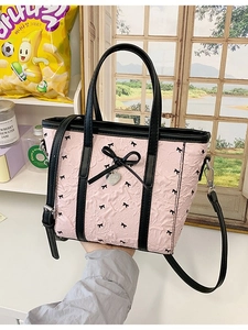 Sac fourre-tout en nylon rose avec nœuds noirs et pendentif cœur, tenu à la main