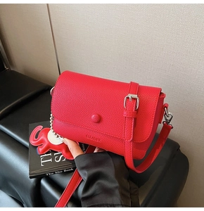 Detail of red square crossbody bag in lychee texture leather with a cute elephant charm