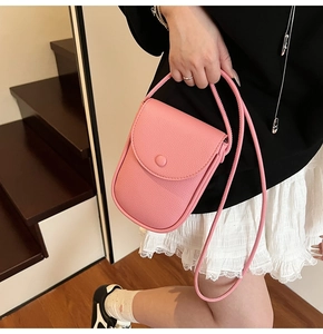 Mini sac pour téléphone en cuir rose grainé porté par un mannequin près d'un escalier