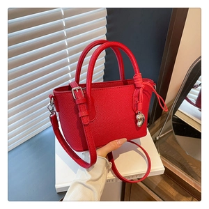 Détail du sac seau en cuir grainé rouge avec breloque cœur et bandoulière amovible