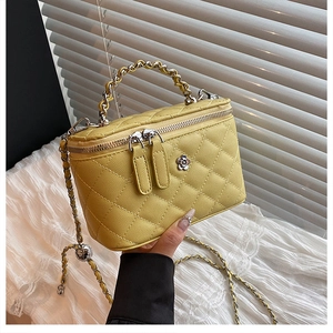 Détail du vanity bag jaune en cuir matelassé avec logo camélia et bandoulière tissée