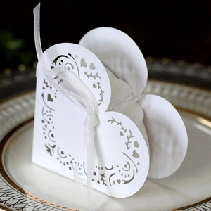 Close-up of white heart-shaped hollow gift box with floral laser cutting and silk ribbon