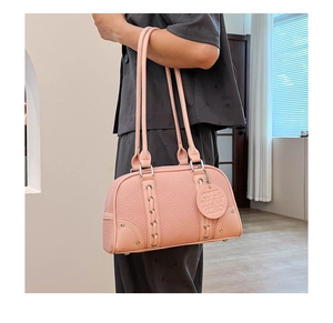 Close-up of pink lychee grain leather bag featuring woven straps and metal eyelet details