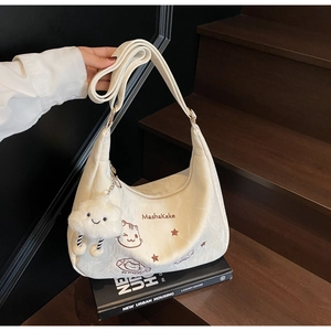 Detail of off-white Hobo bag with cat patterns and cloud plush charm on wooden stairs