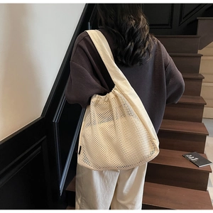 Detail of off-white mesh tote bag with drawstring closure and wide cotton shoulder strap