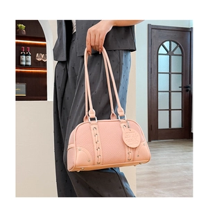 Detailed view of coral pink litchi leather bag with decorative braided straps and metal studs