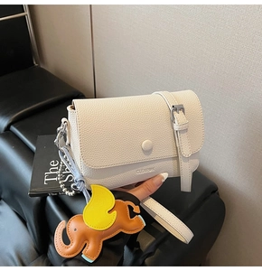 Detailed close-up of white lychee textured shoulder bag with a brown elephant charm