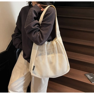 Detail of white mesh tote bag showing breathable hollow texture and casual shoulder strap
