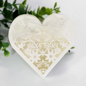 Macro detail of laser-cut floral patterns and white ribbon bow on heart wedding favor box
