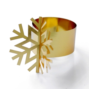 Macro view of golden snowflake napkin ring with polished metallic finish and intricate cutout
