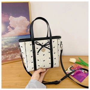 Détail du sac cabas gaufré blanc avec nœuds noirs et pendentif en cœur doré