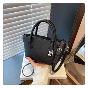 Détail du sac seau noir en cuir grainé avec finitions argentées et pendentif goutte d'eau