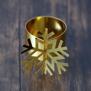 Detailed view of a golden snowflake napkin ring on a dark wooden background