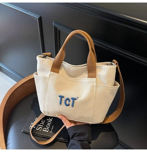 Détail du sac cabas en toile blanc cassé avec broderie TCT bleue et anses marron