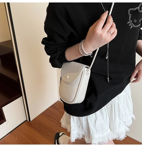 Gros plan détaillé du sac de téléphone en cuir texturé crème porté par le modèle