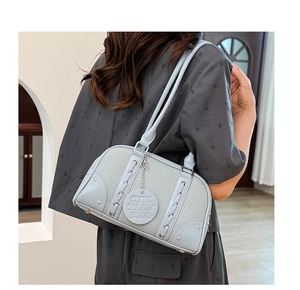 Detail of lychee textured leather bag with metallic eyelets and braided decoration