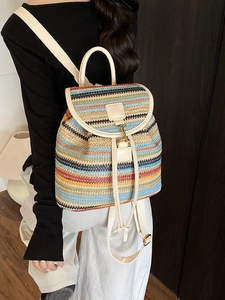 Sac à dos rayé coloré avec sangles beige porté par un mannequin sur fond en bois sombre