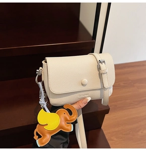 Detail of white lychee leather handbag with cute elephant charm and logo engraving