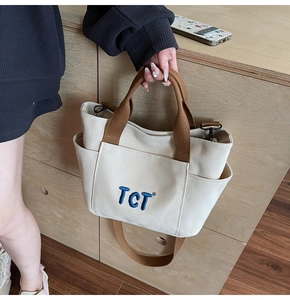 Détail du sac cabas en toile avec broderie TCT, poches latérales et bandoulière réglable
